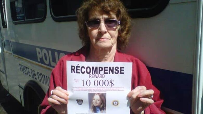 woman holding missing person's poster