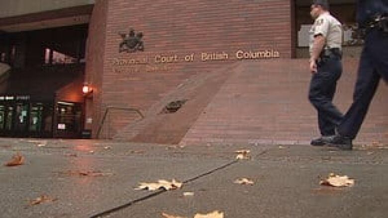 A security guard walks in front of a brick courthouse.