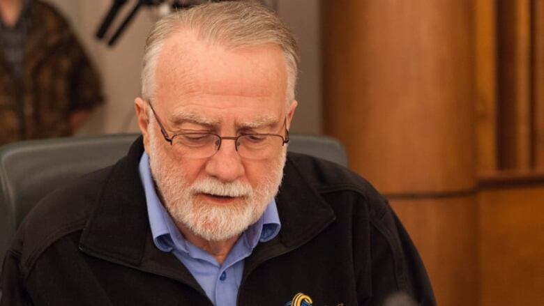 Man sitting in chair in council chambers looking down