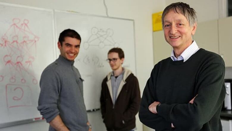 Three smiling men in front of a whiteboard.