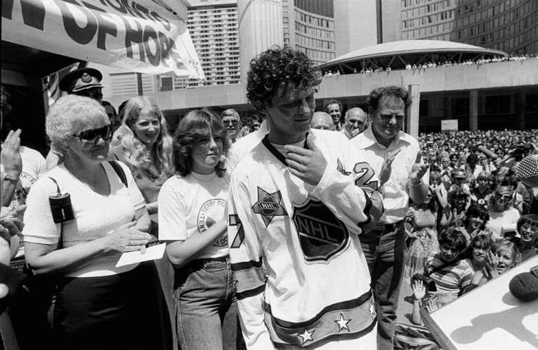 Terry Fox attending a rally at Toronto City Hall with parents Betty, left and Rolly Fox on July 11, 1980. He is wearing an NHL All Star jersey presented to him by Darryl Sittler of the Toronto Maple Leafs. 