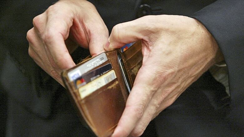 A closeup of a hands opening a brown wallet.