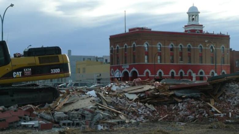 A bulldozer sits on top of a demolished building site.