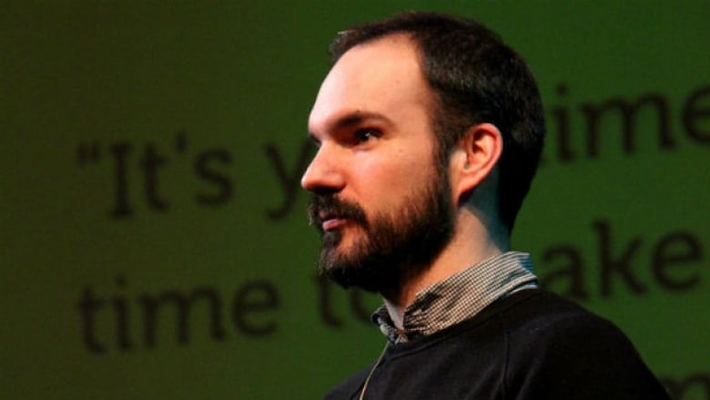 A profile of a man with short brown hair and a beard