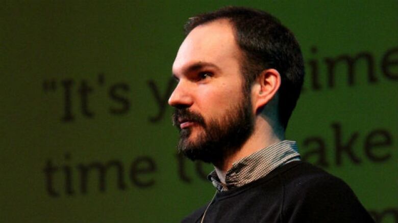 A profile of a man with short brown hair and a beard