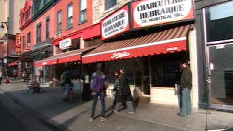 people walk by a deli