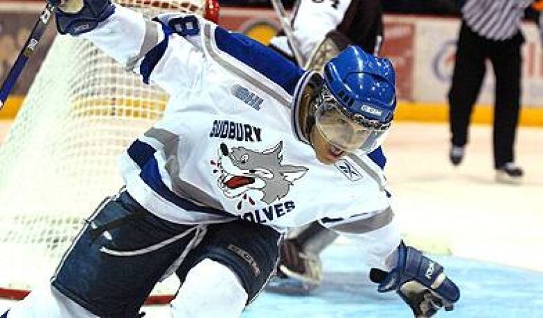 A man wearing hockey equipment falls to the ice.