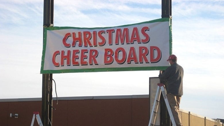 A man stands on a ladder next to a sign that says 