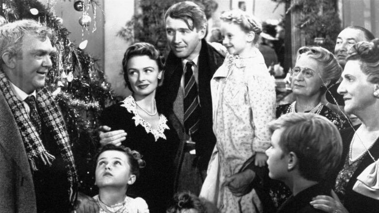 A black and white photo shows George Bailey, played by James Stewart, surrounded by friends and family in the final scene from the movie It's A Wonderful Life. 