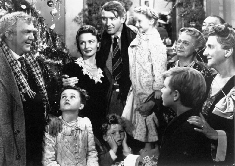 A black and white photo shows George Bailey, played by James Stewart, surrounded by friends and family in the final scene from the movie It's A Wonderful Life. 