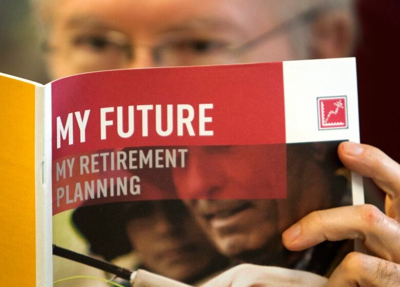 An older man holds a pamphlet with the words My Future My Retirement Plan.