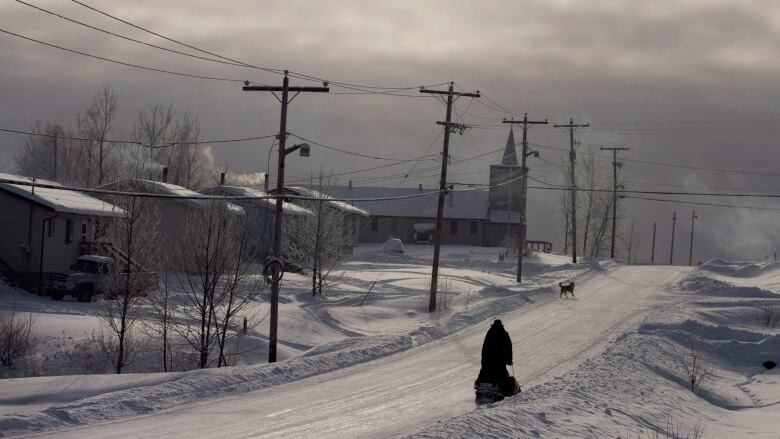 A snowmobile rides down the main street of Fort Hope First Nation in northern Ontario.