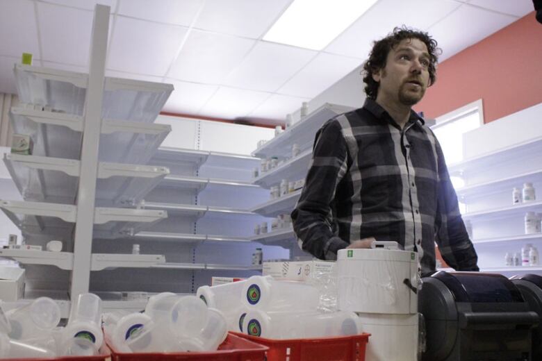 A man stands in front of empty pharmacy shelves 