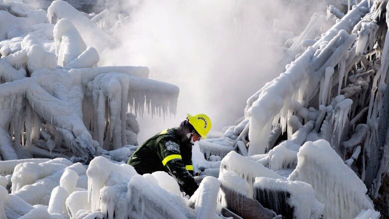 A fireman searches through the ruins of a building.