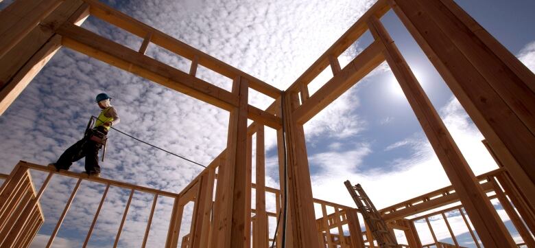 A construction worker walks atop a wood frame for a building.