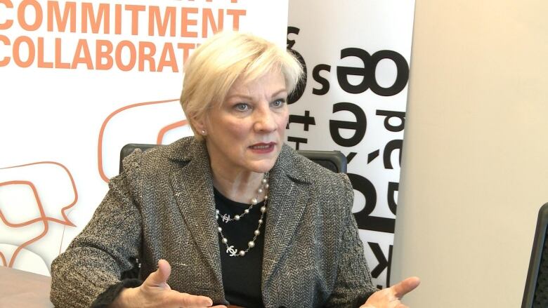 A woman sits behind a desk.