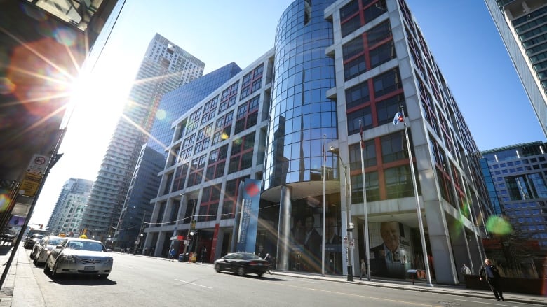 Building with blue glass along urban street setting as sun shines.