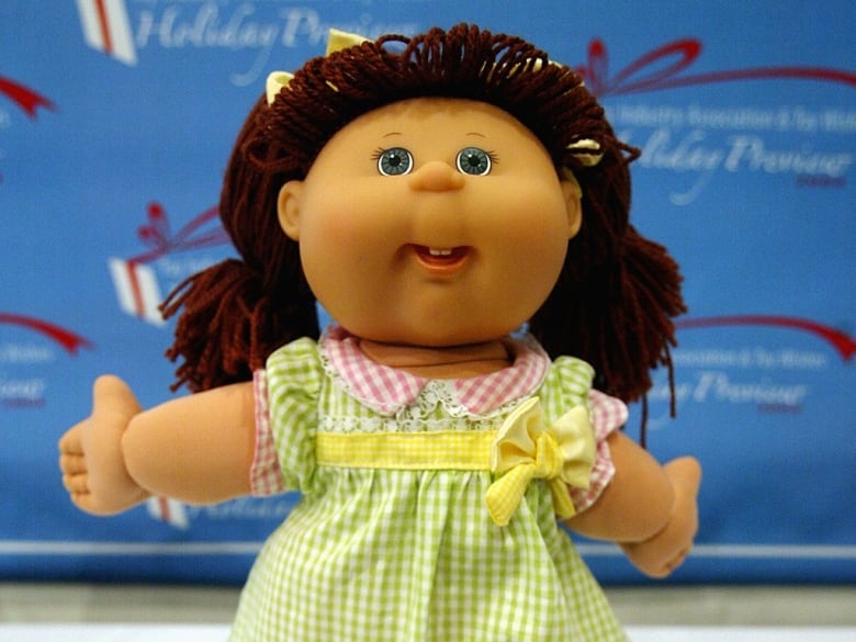 A doll with brown hair made of yarn and a green gingham dress.