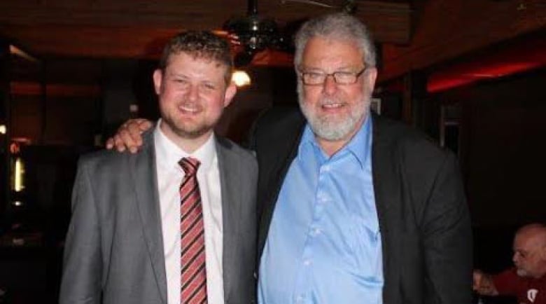 Two men in suits pose for a photo together.