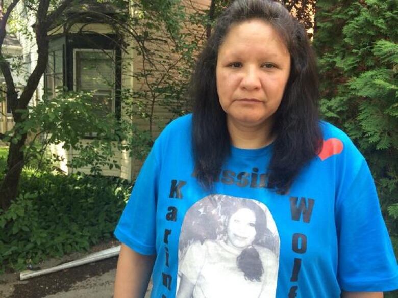 A woman poses for a photo while wearing a shirt that features a picture of a missing loved one.