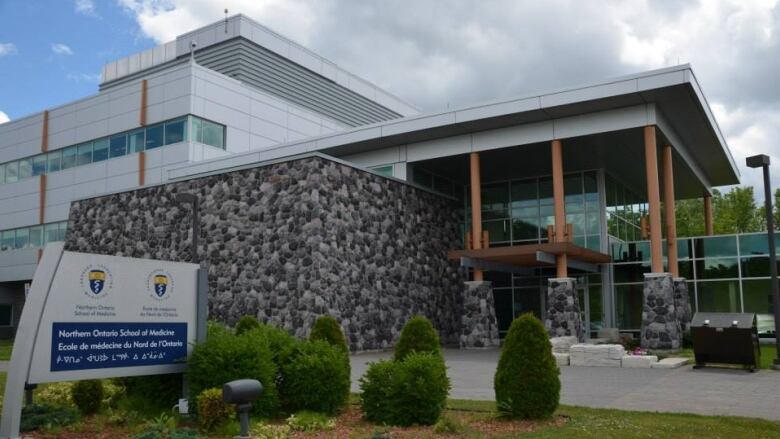 The entrance to NOSM university in Sudbury is a combination of glass windows, stone walls and wooden columns.