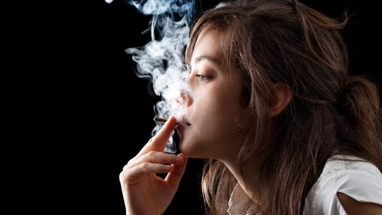 A young woman takes a puff off a cigarette.