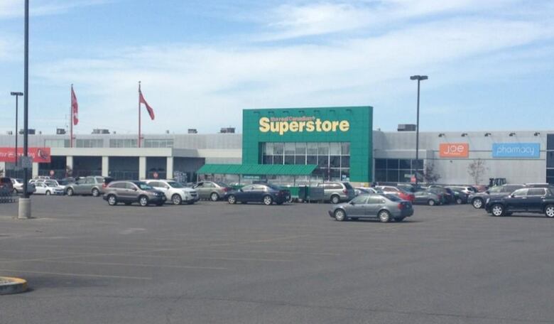 Several cars are seen parked in a large parking lot outside a Superstore.