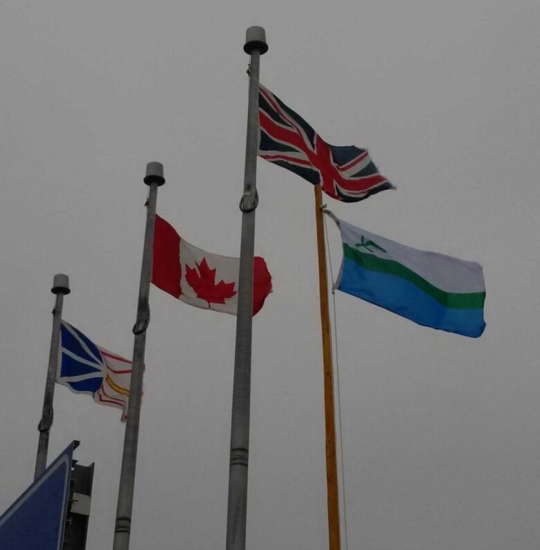 The Newfoundland Flag, The Canadian Flag, The Union Jack and the Labrador Flag raised alongside one another. 