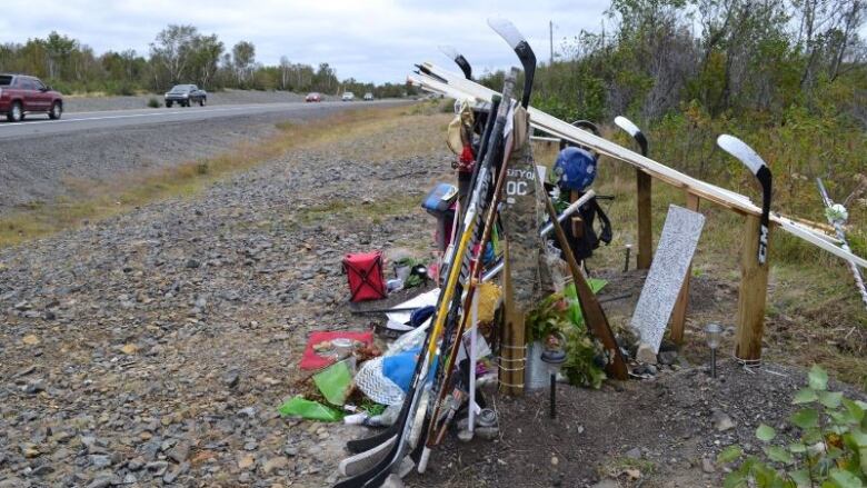 A roadside memorial made up of multiple hockey sticks.