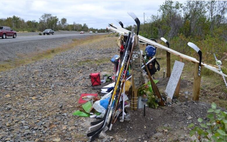 A roadside memorial made up of multiple hockey sticks.