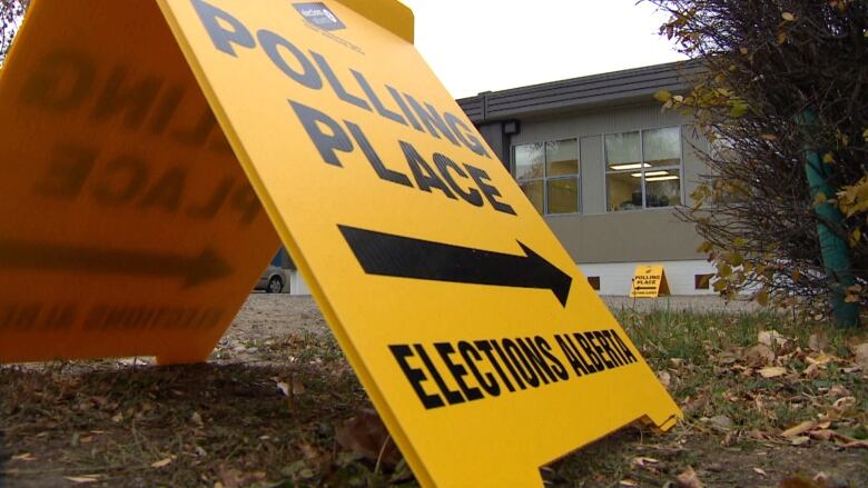 A yellow sign alerting people to where a polling station is.