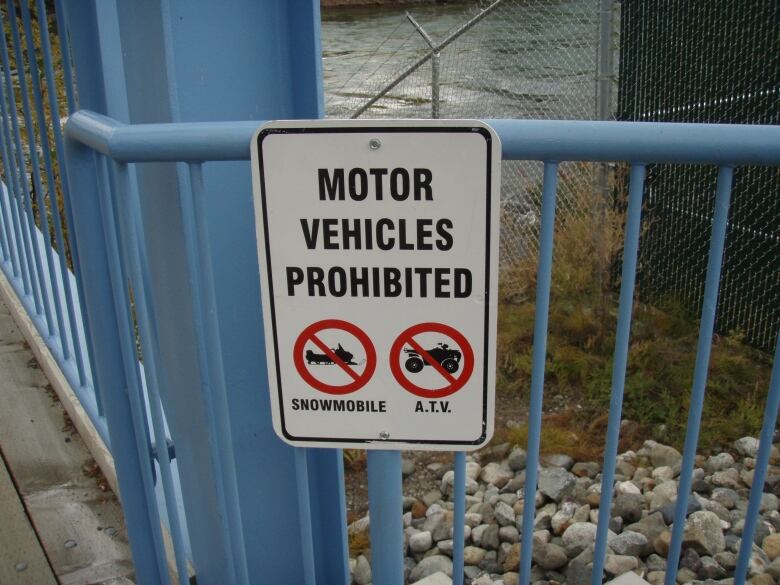 A sign on a blue fence that says Motor Vehicles Prohibited. 