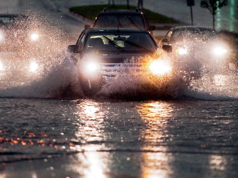 Motorists head through a flooded section of a city street