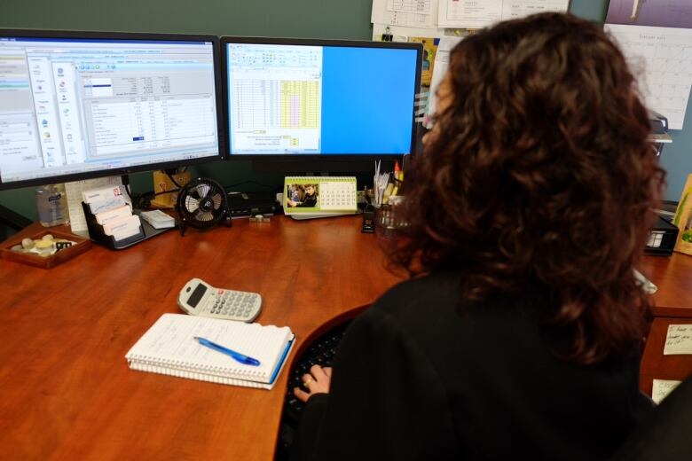 A woman looks at computer screens.