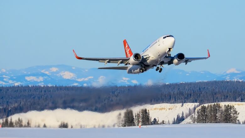 A plane takes off with mountains in the background. 