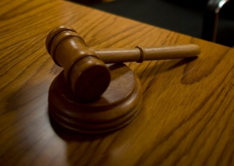 A closeup shows a wooden gavel on a desk.