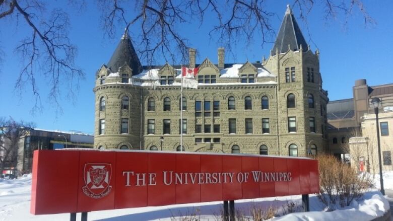 A university campus building is shown in the background, while a red sign, reading 'University of Winnipeg,' is planted in front.