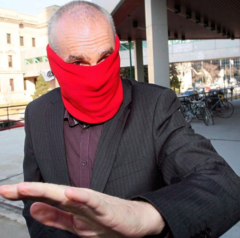 A man wearing a red neckwarmer covering his face exits the Winnipeg lawcourts. 