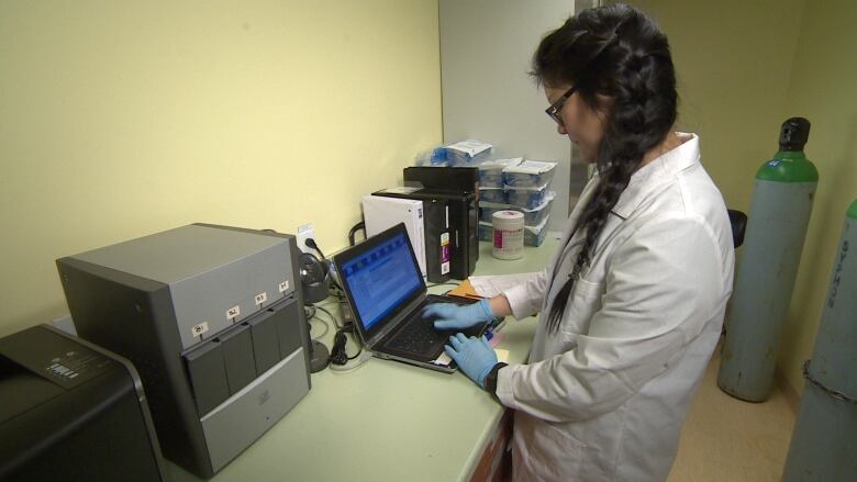 A lab tech stands in front of a GeneXpert machine. 