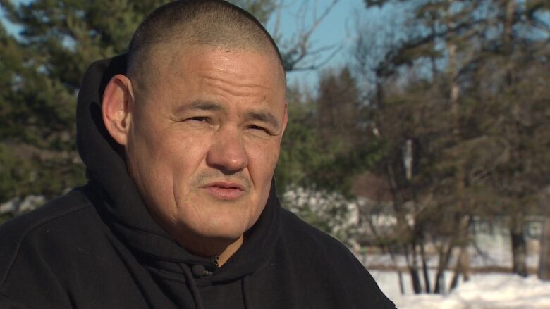 Older Indigenous man looking at camera with neutral expression.