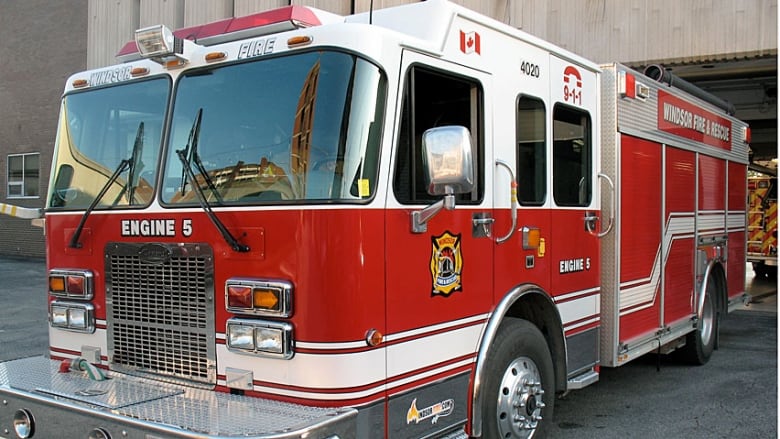 A red fire truck pulling out of an overhead garage at a fire hall. 