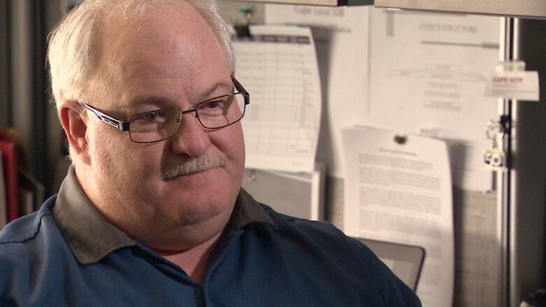 A man wears glasses and a polo shirt.