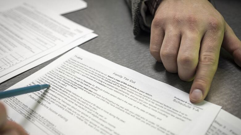 A hand is shown superimposed on a Canadian tax document.