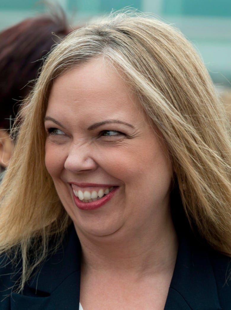 A blond woman smiles as she looks to her left.