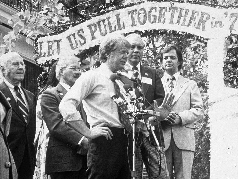 Jimmy Carter speaks on stage with a 'Let Us Pull Together' banner during his national campaign