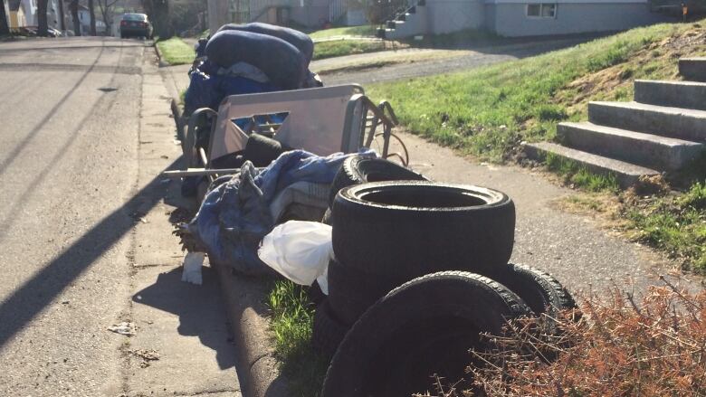 A pile of tires, furniture and other household items sits at the curb waiting for pickup.