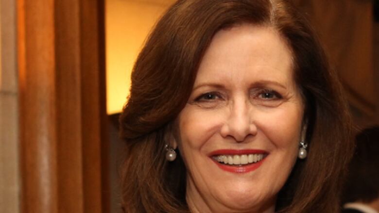 A woman with long auburn hair smiles at the camera