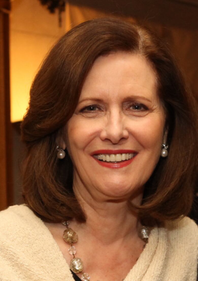 A woman with long auburn hair smiles at the camera