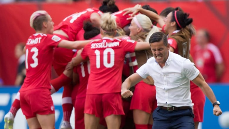 A coach and soccer players dressed in red celebrating a win. 