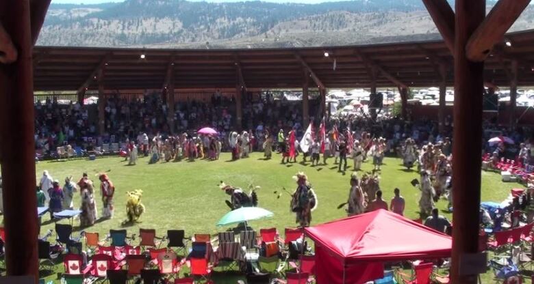 A number of people are seen in a circle, with chairs and fair merchandise around them.